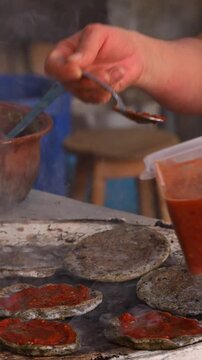 Mexican food, Corn gorditas or memelas being prepared with red salsa by hand