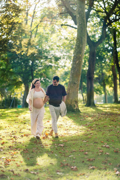 Pregnant couple walking happily in a sunny park