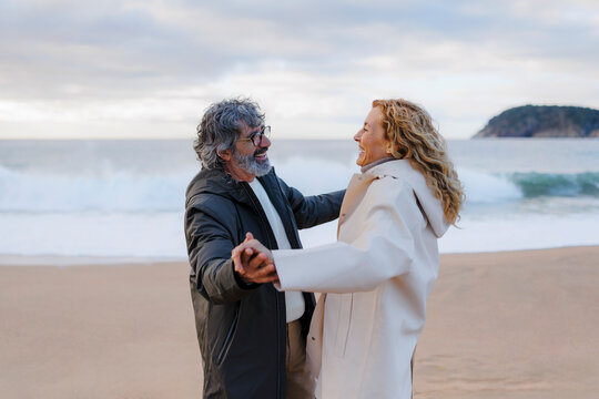 Happy couple dancing on beach enjoying winter