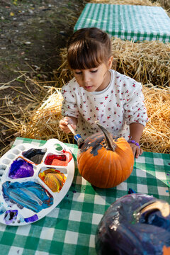 Girl painting pumpkin for fall Halloween craft activity