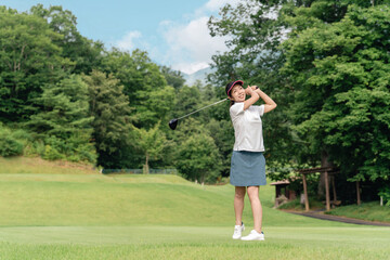 Female golfer playing golf on a golf course (tee shot, golf competition)