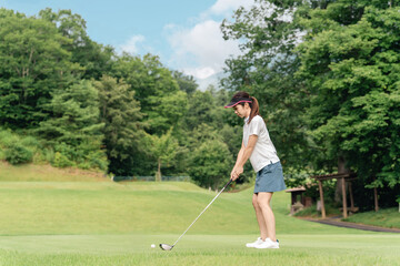 Obraz premium Female golfer playing golf on a golf course (tee shot, golf competition)