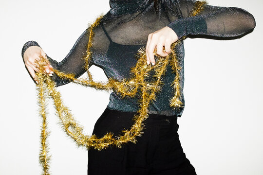 Person wearing glitter shirt and holding golden shiny christmas ribbon