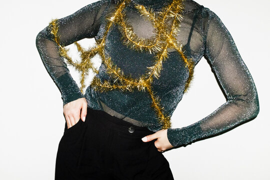Person wearing glitter shirt and holding golden shiny christmas ribbon