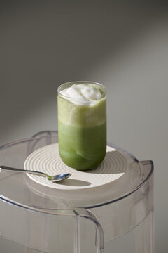 Refreshing matcha latte with foam served on a stylish plate and table