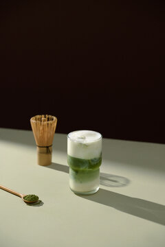 Refreshing matcha latte with whisk and matcha powder