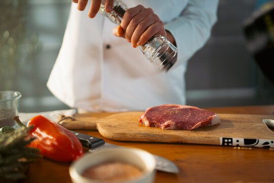 Chef prepares steak with seasoning
