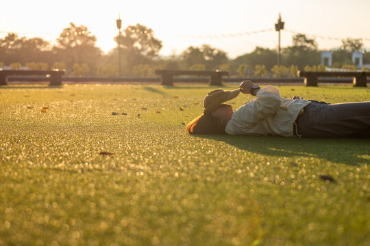 Relaxed lifestyle moment lying on green grass at sunset in a park