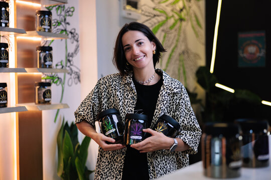Woman holding jars of cannabis in a dispensary.