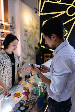 Customer examines product at counter in modern retail store.