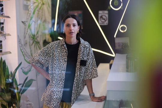 Woman in leopard print shirt stands in modern store.