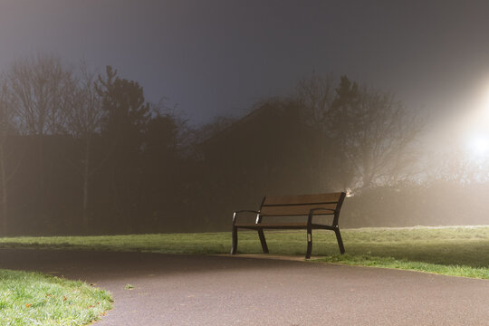 A bench on a quiet foggy winters night in a park