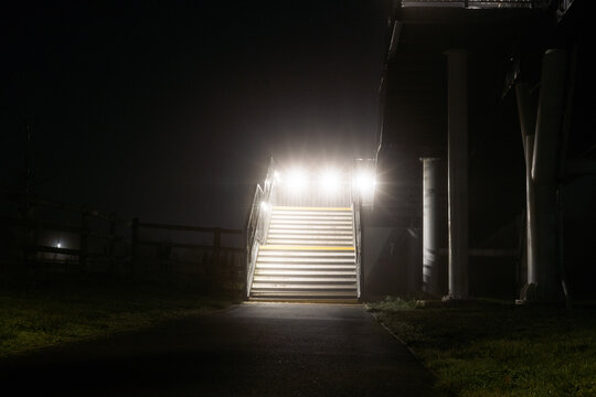 Steps to a modern foot bridge on a foggy winters night