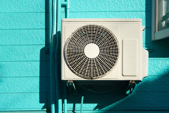 Air conditioner on bright blue wall on a sunny day. 