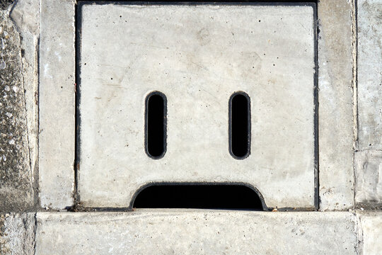 Cute Concrete Drain Cover With a Sad Face