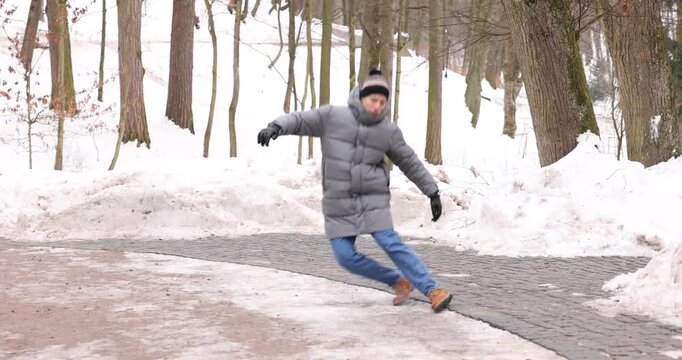 Young man falling on slippery pathway covered in ice outdoors