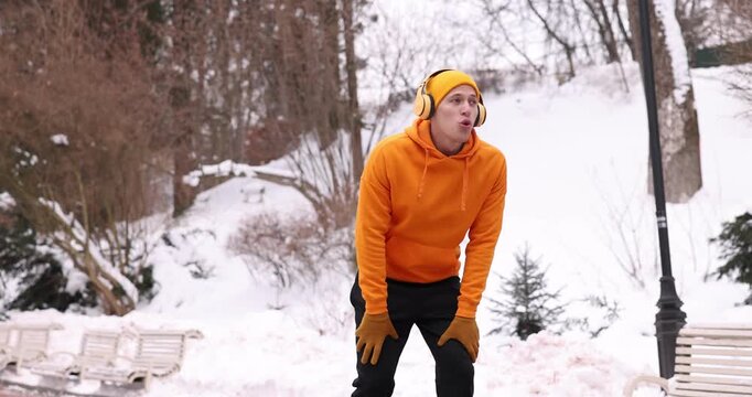 Man with headphones stopping for rest during run in winter park