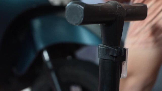 Man using manual hand pump to inflate motorcycle tire