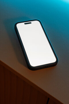 Smartphone with blank screen on tabletop in blue light