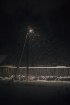 snow falling under streetlamp at night