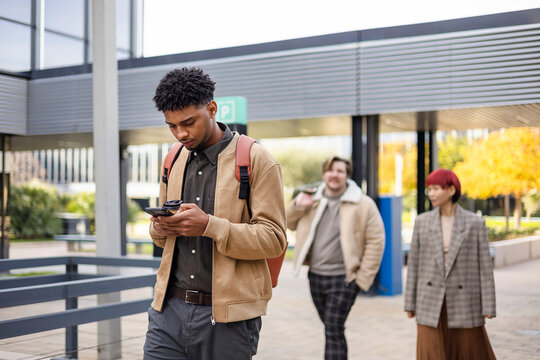 Young student walking on university campus using smartphone