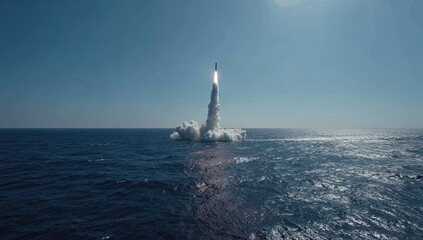 Rocket ascends from ocean, trailing plume of smoke against clear sky