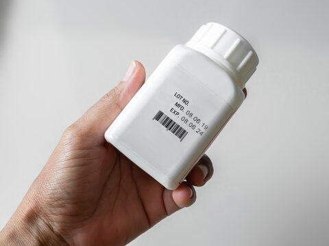 Expire drugs check, finger woman holding bottle mfg and exp date infomation, supplement food product, blur medicine label, blur text.