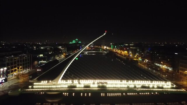 Night aerial of a lit cable-stayed bridge over a river.
