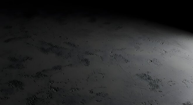 A dark, textured surface resembling a desolate planetary landscape or moonscape with subtle light variations and a distant horizon.