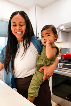 Mother carrying Child Cooking in the Kitchen 