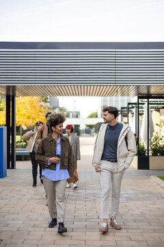 Diverse students walking and talking on modern campus