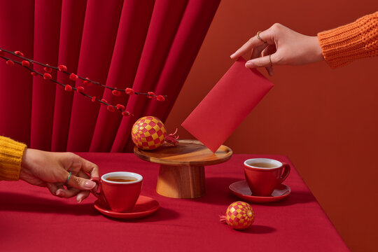 A person's hand presents a red envelope over a festive table