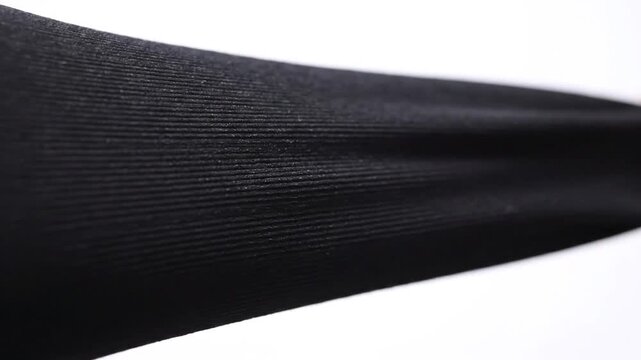 Close-up of black ribbed fabric being stretched, showing texture and elasticity