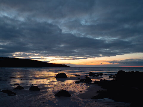 Sunset at rocky coast over calm sea and rocks