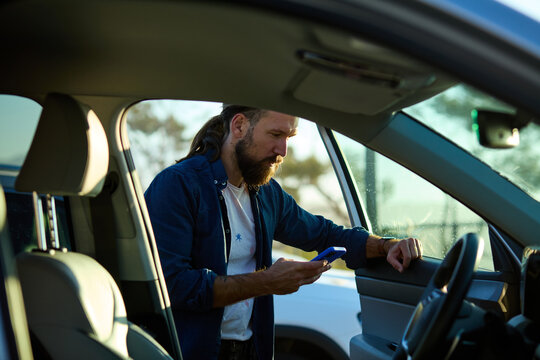 Man enters the car, holding a mobile phone