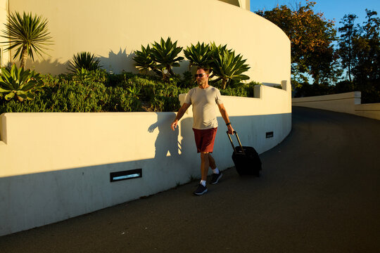 Man walks confidently, pulling a suitcase behind him
