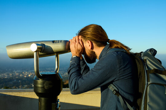 Man observes the city with static binoculars