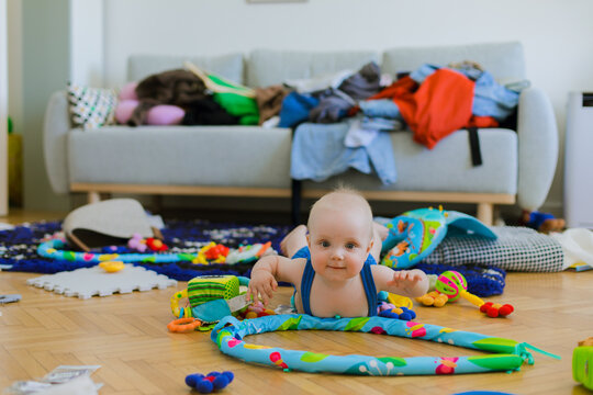 A big mess in a living room, a child is lying on carpet