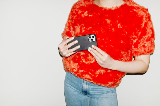 Person wearing fashion style furry top and holding modern smartphone