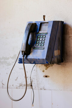 Vintage blue public payphone mounted on a concrete wall