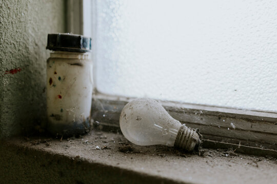 Dusty bulb and jar by a window on a neglected ledge
