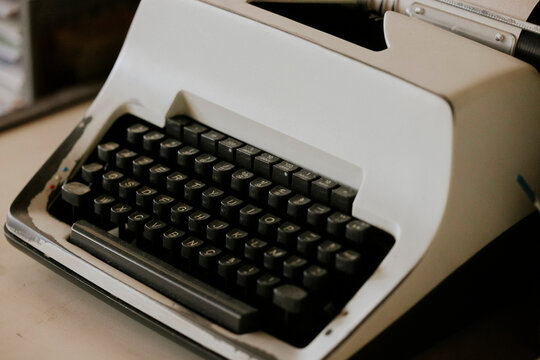 Vintage white typewriter on a wooden desk close-up