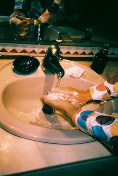 lathering his hands with a bar of soap at a bathroom sink, 35mm film