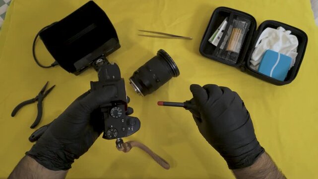 Photographer using a specialized brush on the camera body.