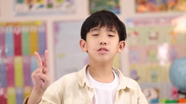 Asian Schoolboy Counting Numbers With Fingers In Classroom