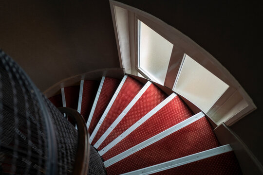 Spiral Staircase With Red Carpet and Light From Windows