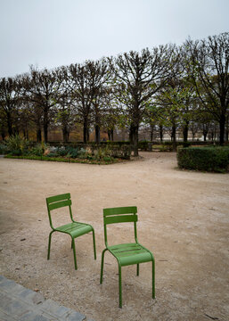 Two Green Chairs in a Garden Surrounded by Bare Trees