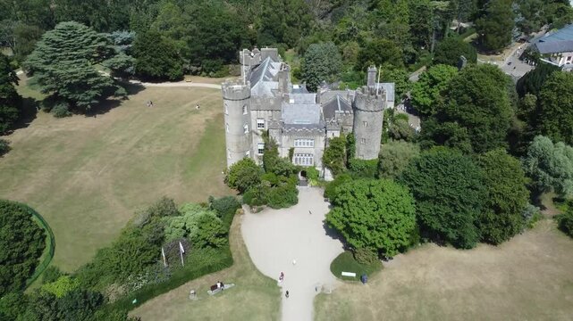 An aerial show of a castle in Ireland, the beauty of tree that involves the castle 