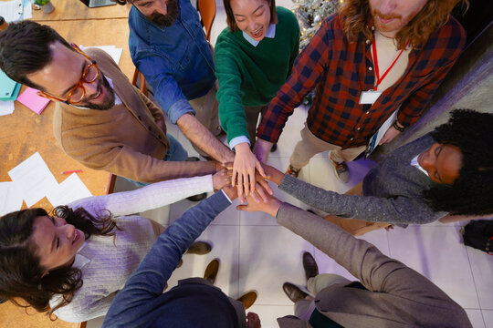 Team members join hands in office
