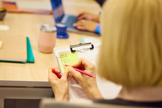 Woman writes a reminder on a sticky note